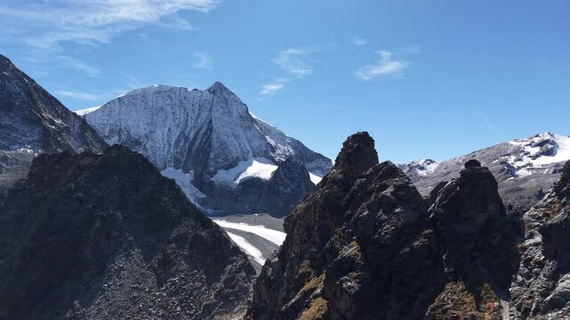 Aerial flyover above the mountain peaks next to Glacier de Cheilon with a pan down view from the mountain peaks of the Swiss Alps