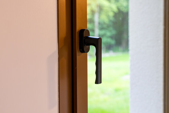 D&eacute;tail de poign&eacute;e de fen&ecirc;tre ou porte-fen&ecirc;tre moderne avec vue sur l&rsquo;ext&eacute;rieur dans un int&eacute;rieur contemporain.