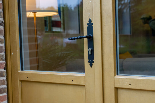 D&eacute;tail d&rsquo;une porte vitr&eacute;e en bois avec poign&eacute;e en ferronnerie dans une r&eacute;novation au style traditionnel.