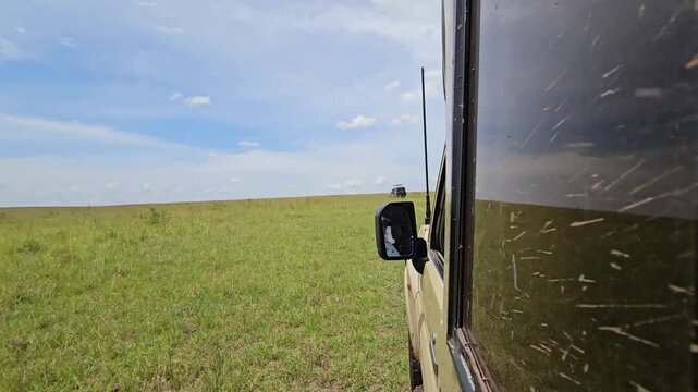 Safari vehicle driving along the Tanzania border in Masai Mara, Kenya, sunny day