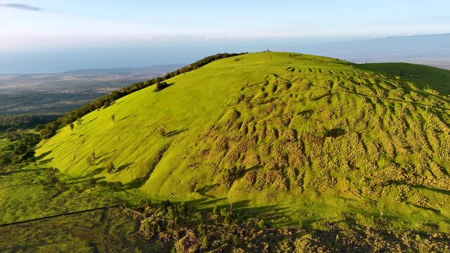 Aerial view of Puu Waawaa cinder cone with lush green slopes and distant ocean horizon in Hawaii County, Hawaii, United States.