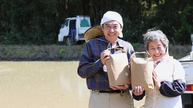 お米を手に笑顔を見せるシニア農家夫婦