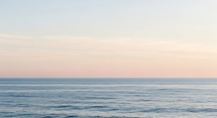 Fototapeta premium Calm ocean horizon with soft pastel sky at dawn or dusk, a serene natural landscape scene.