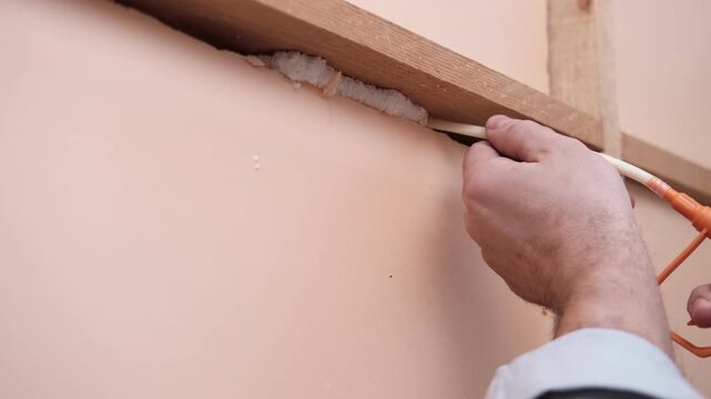 Applying thermal insulation foam with a gun. Using polyurethane foam along wall joints. Expanding the material. Sealing joints and soundproofing walls. Interior renovation. Close-up. Copy space.