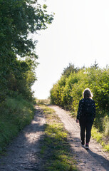 Fototapeta premium Woman walking on a dirt road on a sunny day, lifestyle and nature concept.