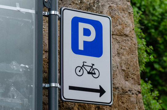 bicycle parking sign with adjacent cycle path indication, urban mobility concept for sustainable transport, road signage for cyclists, bike lane infrastructure, eco friendly in modern city streets
