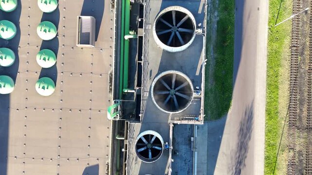Aerial view of industrial cooling system with large fans and green ventilation units on a factory roof, showcasing continuous airflow and operational efficiency in a manufacturing environment