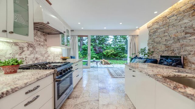 Bright modern kitchen with marble counters opening to lush garden patio and outdoor living space