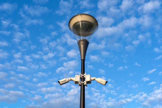 Contemporary outdoor lighting system with security surveillance technology and monitoring cameras under dramatic sky