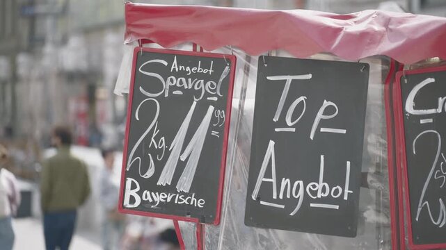Outdoor street food market with german signs offering fresh asparagus and other products