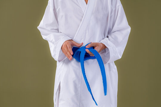 Boy standing in karate uniform tightening his belt. Highlights discipline, posture control, and traditional martial arts preparation.