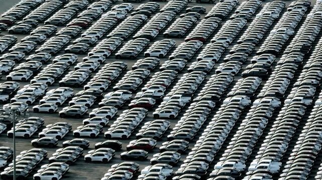Drone aerial view of newly manufactured cars lined in perfect rows at an automotive plant, symbolizing industrial efficiency, smart manufacturing, and large scale vehicle distribution worldwide. 4k.
