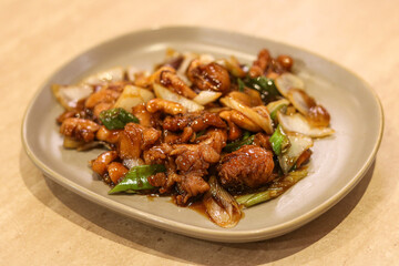Fototapeta premium Kung Pao chicken, featuring tender stir-fried chicken pieces glazed in a savory sauce, tossed with peanuts and onions.
