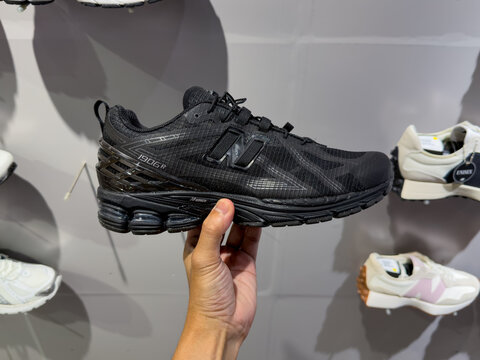 KUALA LUMPUR, MALAYSIA - FEB 02, 2026: Close up of a hand holding a black New Balance 1906R sneaker inside a retail shoe store.