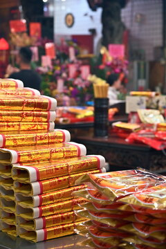 Yilan, Taiwan - Feb 21, 2026: Stacked gold joss paper with temple seal imprint, divination cup on altar, two blurred worshippers, warm gold red light, Cihui Temple Yuanshan Yilan County.