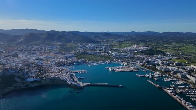 Left side aerial view of Ibiza city, taken from an airplane cockpit, with a view of the harbor, and the old town on the hill.