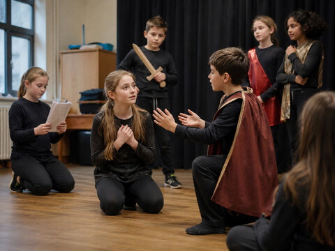 School students rehearsing a drama scene in a theater class.