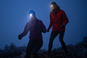 Fototapeta premium Night Trail Running Couple With Headlamps On Frosty Mountain Path Training Together