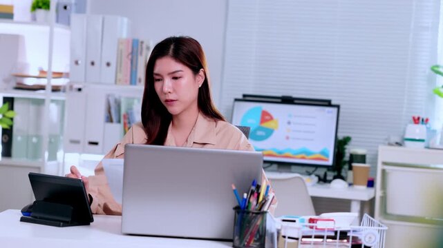 Businesswoman office laptop paperwork desk finance accountant employee professional reviewing document modern workspace, Asian woman focused corporate remote work productivity, charts and analysis