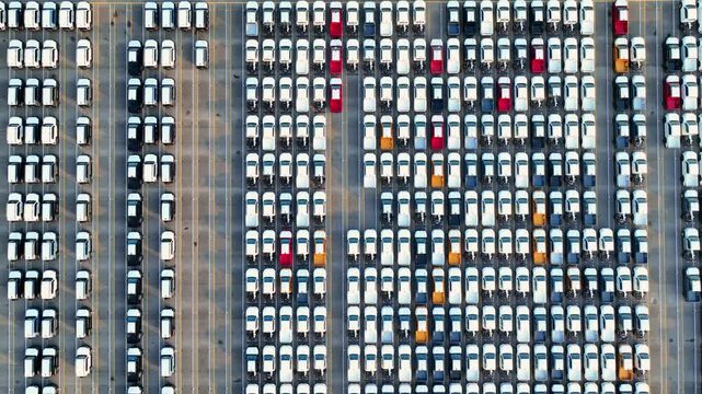 An aerial view of cars parked at a futuristic automobile manufacturing facility, emphasizing industrial automation, carbon reduction goals, and the evolution of smart transportation worldwide. 4k.
