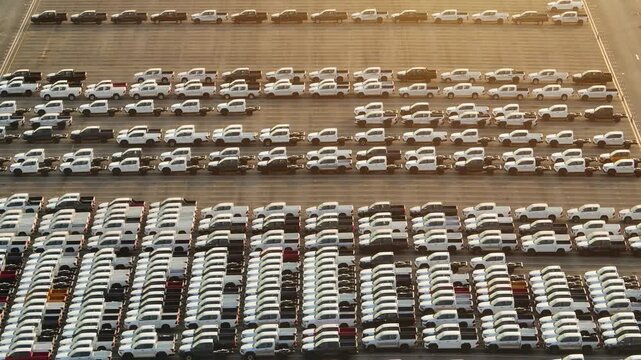 An aerial drone photograph of rows of cars prepared for distribution from a vehicle manufacturing plant, emphasizing innovation, industrial productivity, and the future of smart transportation. 4k.
