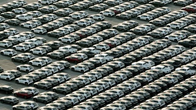 Drone view of rows of vehicles prepared for shipment from a large car manufacturing plant, reflecting automation, international trade, and evolving transportation industries worldwide. 4k.
