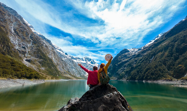 Travelers couple team look on the mountain landscape. Travel and active life concept as Adventure travel in the mountains region in lake marian fiordland national park.