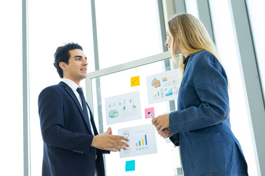 Man and woman businesspeople planning business strategy while looking at infographic on wall. Business, education and office concept.