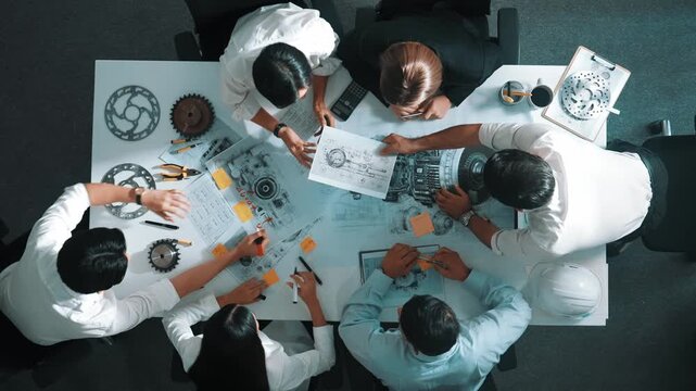 Top view of engineer pointing at turbine engine at meeting table with equipment. Aerial view of professional project manager talking and discussing about electronic generator system. Alimentation.