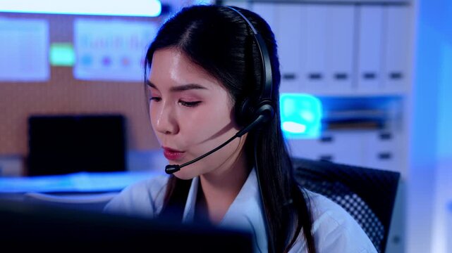 Customer service agent wearing headset working computer modern office call center support communication, focused expression, telemedicine healthcare consultation online patient helpdesk operator