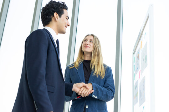 Man and woman businesspeople planning business strategy while looking at infographic on wall. Business, education and office concept.