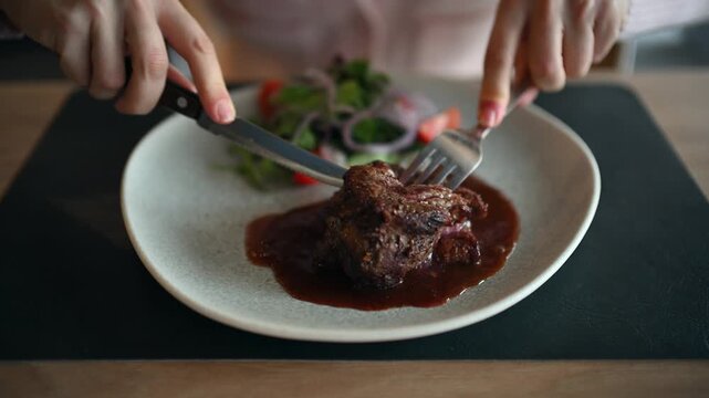 Woman hands cutting juicy beef steak with knife and fork in restaurant close up cinematic food clip.