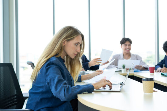 Teamwork. Side view of white woman in a office using laptop during creative meeting and drink coffee. Concept of business, office, finance, open space.