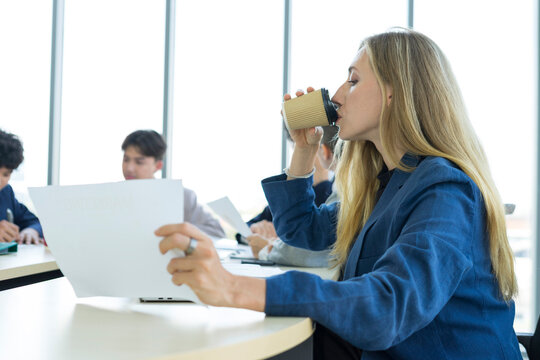 Teamwork. Side view of white woman in a office using laptop during creative meeting and drink coffee. Concept of business, office, finance, open space.