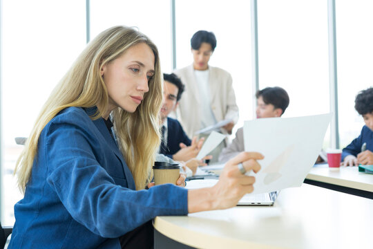 Teamwork. Side view of white woman in a office using laptop during creative meeting and drink coffee. Concept of business, office, finance, open space.
