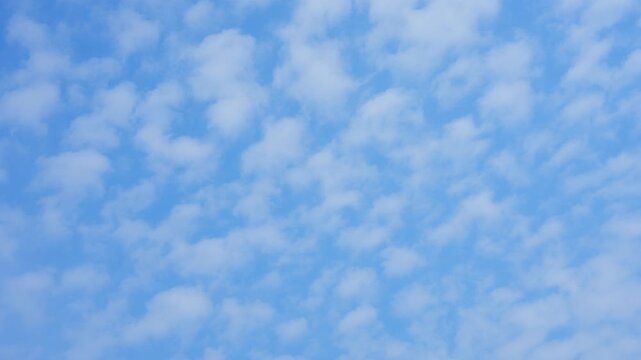 A blue sky timelapse video footage featuring soft altocumulus cloud patterns spreading across the atmosphere, symbolizing weather stability, peaceful skies, climate balance, and natural harmony. 4k.
