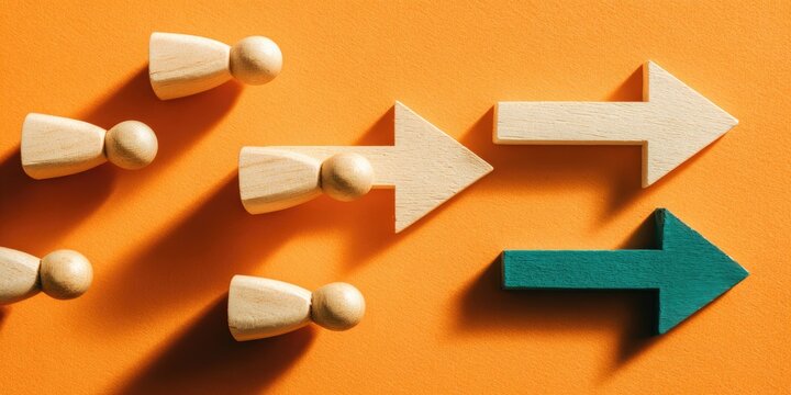 Wooden figures follow arrows on orange background, one deviates
