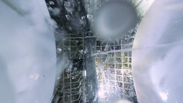 Inside Slow Motion View of Dishwasher with Water Spray and Rotating Arm