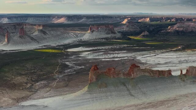 Aerial view of Bozjyra limestone cliffs and buttes rising from the desert floor under a soft sky in Aktau, Mangystau Region, Kazakhstan.