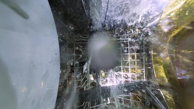 Inside Slow Motion View of Dishwasher with Water Spray and Rotating Arm