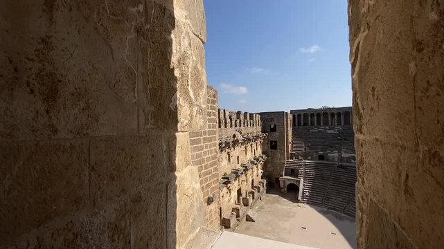 Reveal shot of Aspendos Roman Theatre interior with monumental facade and stone seating in Turkey