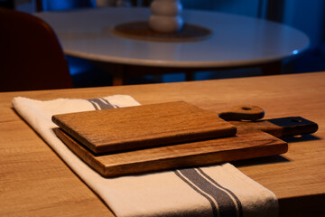 Obraz premium Wooden cutting boards with napkin on table in dark kitchen at night