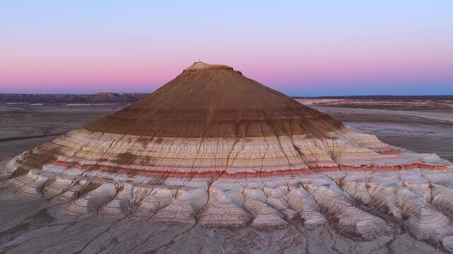 Aerial view of Gora Bokty mountain with its unique colorful layers and eroded slopes under a soft twilight sky in Karakiya District, Mangystau Region, Kazakhstan.