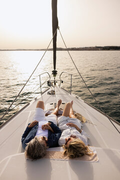 Mature couple relaxing on sailboat deck at sunset