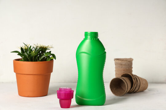 Bottle of plant fertilizer on light background