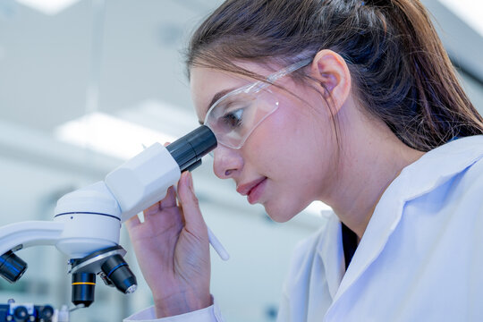 Scientist looks through microscope in laboratory during work hours