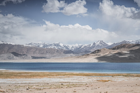 Mountain landscape, a cold high-altitude lake against the backdrop of rocky peaks and ridges with snow and glaciers, a panorama in the Tien Shan Mountains in the Pamirs, a lake with waves
