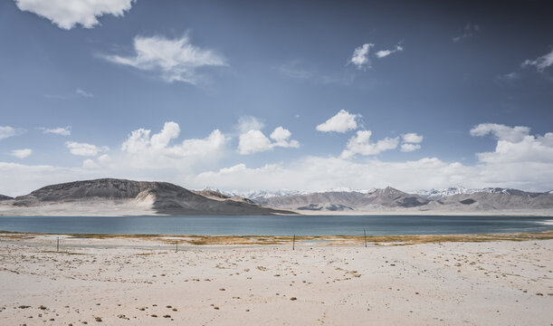 Mountain landscape, a cold high-altitude lake against the backdrop of rocky peaks and ridges with snow and glaciers, a panorama in the Tien Shan Mountains in the Pamirs, a lake with waves