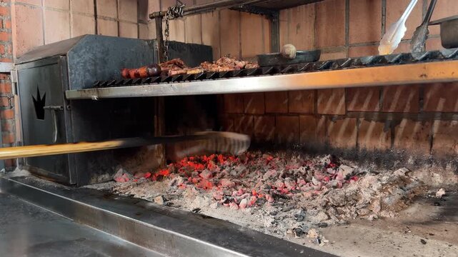 Chef raking hot coals for traditional argentinian barbecue asado