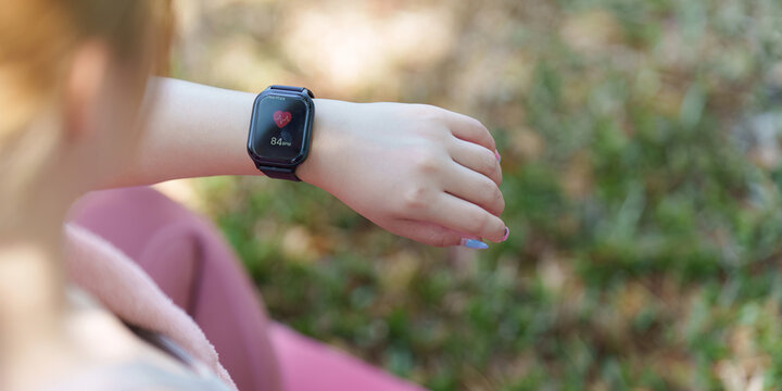 Asian woman checking heart rate on smartwatch during outdoor fitness activity